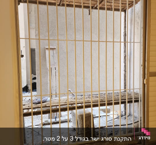 סורגי מתכת לבנים על חלון עם נוף חיצוני